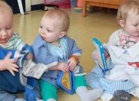 Children's nursery school, babies reading books on floor